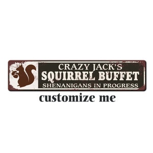 May include: A rustic metal sign with a brown squirrel holding nuts. The sign reads "Crazy Jack's Squirrel Buffet Shenanigans in Progress".
