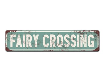 May include: A vintage-style metal sign with a distressed, rusty look. The sign is green with white lettering that reads "FAIRY CROSSING".