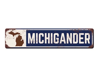 May include: A rusty metal sign with a white background and blue text. The sign says "MICHIGANDER" and features a brown silhouette of the state of Michigan.