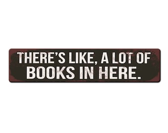 May include: A black and brown rectangular sign with white text that reads "THERE'S LIKE, A LOT OF BOOKS IN HERE."
