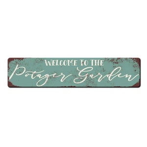 May include: A rustic, teal-colored metal sign with a distressed finish. The sign reads "Welcome to the Potager Garden" in white script.