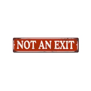 May include: A rectangular, rusty red metal sign with the words "NOT AN EXIT" in white, distressed lettering. The sign has a weathered appearance, suggesting it's been exposed to the elements. The sign is rectangular and has a dark brown border.