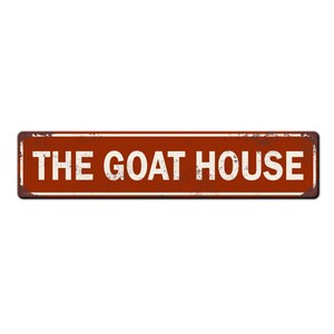 May include: A rusty red metal sign with white text that reads "THE GOAT HOUSE".