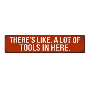 May include: A red metal sign with white text that reads "There's like, a lot of tools in here."