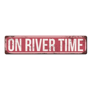 May include: Red metal sign with white text that reads "ON RIVER TIME".