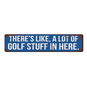 May include: A blue and brown rectangular sign with white text that reads "THERE'S LIKE, A LOT OF GOLF STUFF IN HERE."