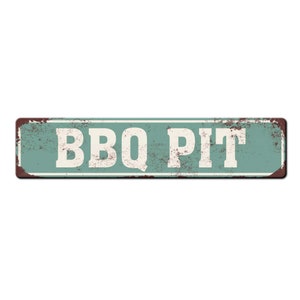 Pode incluir: Uma placa de metal verde r&uacute;stica com o texto "BBQ PIT" em letras brancas. A placa tem um aspecto desgastado e desbotado, o que sugere que foi usada ao ar livre por muito tempo.