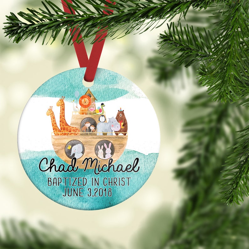 May include: A round, blue and white Christmas ornament with a watercolor design of Noah's Ark with animals. The ornament has the text "Chad Michael Baptized in Christ June 3, 2018".