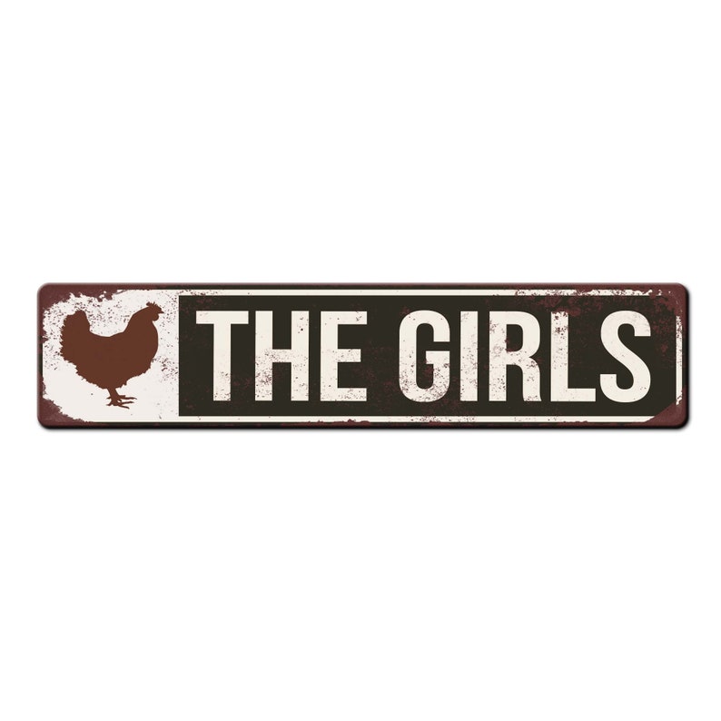 Puede incluir: Un letrero de metal oxidado con fondo blanco y texto negro que dice "THE GIRLS". Una silueta marr&oacute;n de una gallina est&aacute; en el lado izquierdo del letrero.