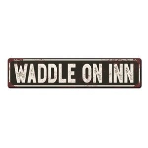 May include: A rusty metal sign with the text "Waddle On Inn" in white letters on a black background.