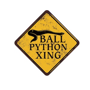May include: A weathered, diamond-shaped sign with a yellow background and a brown border. The sign features a black illustration of a snake and the words "BALL PYTHON XING" in bold, black letters. The sign has a distressed, vintage appearance.