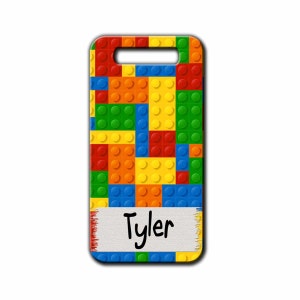 May include: A colorful phone case with a Lego block pattern and the name "Tyler" written on a white label.
