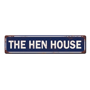 May include: A blue and white metal sign with the text "THE HEN HOUSE" in white lettering. The sign has a rustic, weathered look.