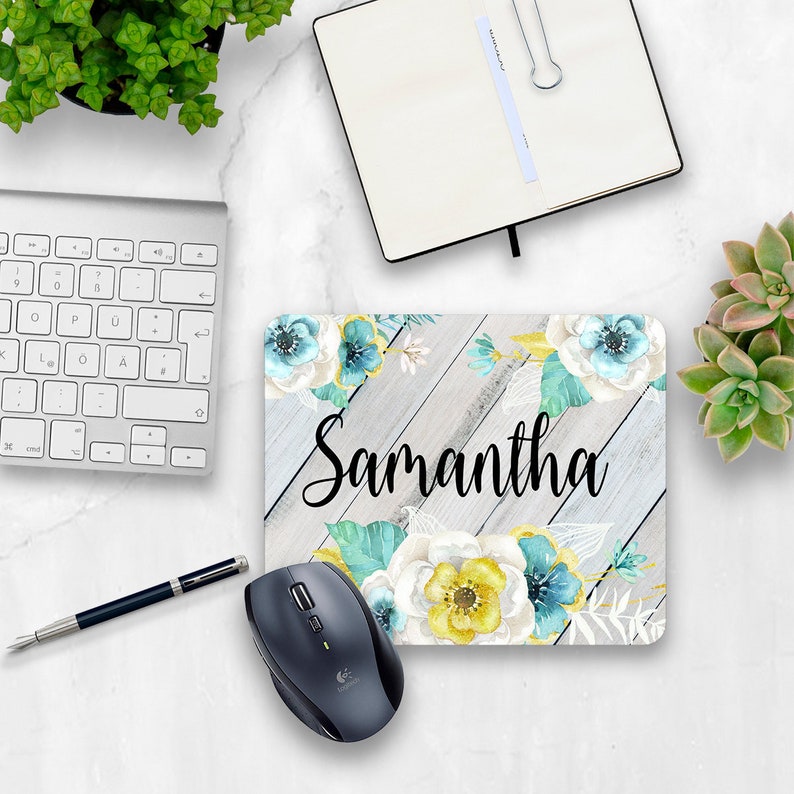 May include: A personalized mouse pad with a white woodgrain background and a floral design in shades of blue, yellow, and white. The name "Samantha" is written in black cursive lettering.