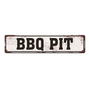 Pode incluir: Uma placa de metal branco com uma borda marrom enferrujada. A placa diz "BBQ PIT" em letras pretas.