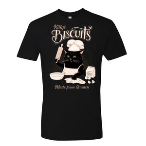 May include: Black t-shirt with a graphic of a cat wearing a chef's hat and holding a rolling pin. The text "Kitty's Biscuits Made from Scratch" is printed on the shirt.