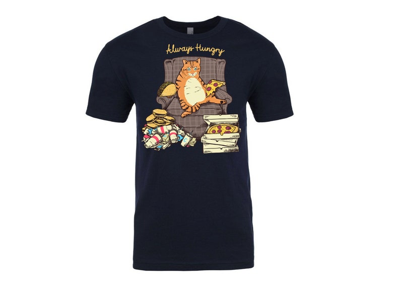 May include: A navy blue t-shirt with a graphic of an orange cat sitting in a chair with a pizza and a taco. The cat is surrounded by empty food containers and the text "Always Hungry" is printed above the cat.