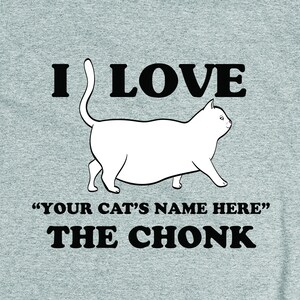 May include: A gray t-shirt with a white cat illustration and the text "I love "YOUR CAT'S NAME HERE" the CHONK".