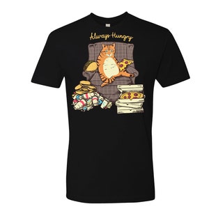 May include: A black t-shirt with a graphic of a cartoon orange cat sitting in a chair with a pizza and a taco. The text "Always Hungry" is above the cat.