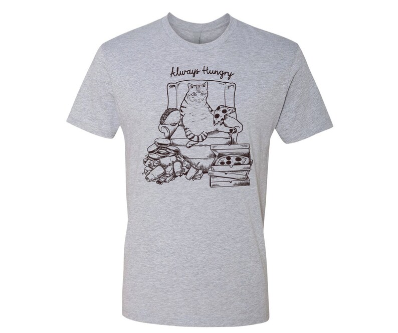 May include: A gray t-shirt with a black and white illustration of a cat sitting in a chair surrounded by pizza boxes and food. The text "Always Hungry" is printed on the shirt.