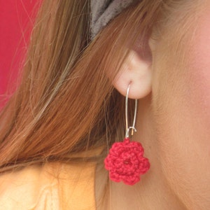 May include: A pair of red crocheted flower earrings with silver hooks.