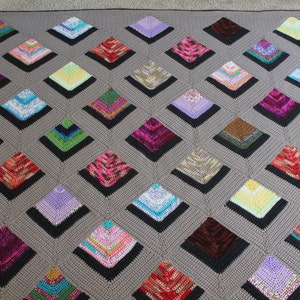 May include: A gray crocheted blanket with a diamond pattern. Each diamond is filled with a different colored crocheted square.