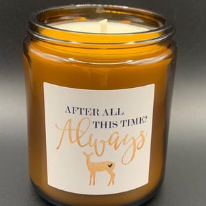 May include: Amber glass candle with a white label that reads "After all this time? Always" in a cursive font. A gold deer with a heart on its back is printed on the label.