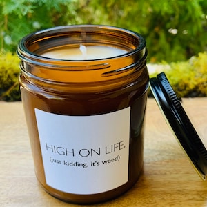 May include: A brown glass candle jar with a white label that reads "HIGH ON LIFE. (just kidding, it's weed)".