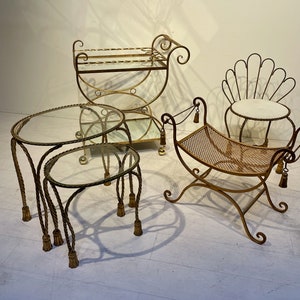 Puede incluir: Una colecci&oacute;n de muebles vintage de metal dorado. Incluye dos mesas nido con tapas de cristal y patas en forma de cuerda, un carrito de servicio, un banco con asiento tejido y una silla en forma de concha.