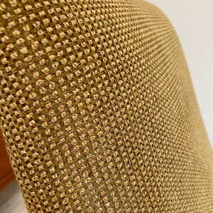 May include: Close-up of a chair back with a textured, woven fabric. The fabric has a repeating pattern of small, square-like shapes in shades of tan, brown, and a hint of red. The overall appearance is neutral and warm.