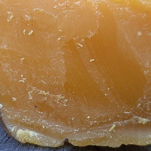 May include: A large block of yellow beeswax. The beeswax has a rough, textured surface.