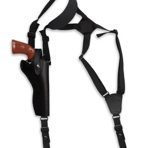 Könnte beinhalten: Schwarzes Lederholster mit Schultergurt zum Tragen einer Pistole. Das Holster hat einen Gurt, der über die Schulter geht, und einen weiteren Gurt, der um die Taille geht.