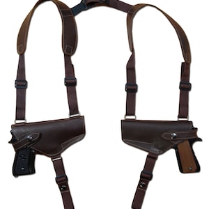 Pode incluir: Um coldre duplo de couro marrom com duas pistolas presas. O coldre tem tiras ajustáveis para um ajuste confortável.