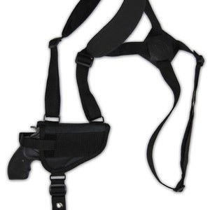 May include: Black shoulder holster with a handgun. The holster has adjustable straps, a padded shoulder piece, and a secure pouch for the firearm. The design includes a vertical strap with a snap closure and a horizontal strap for stability.