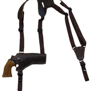 Może przedstawiać: Brązowa skórzana kabura z przymocowaną bronią palną. Kabura jest przymocowana do brązowego skórzanego uprzęży z regulowanymi paskami.