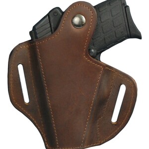 K&ouml;nnte beinhalten: Ein braunes Lederholster f&uuml;r eine kleine Pistole. Das Holster hat zwei G&uuml;rtelschlaufen und einen Druckknopfverschluss.