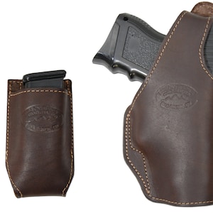 Może przedstawiać: Brązowa skórzana kabura z obszytym brzegiem i logo "Southwestern Saddlery" z przodu. Kabura jest przeznaczona do przechowywania pistoletu i zapasowego magazynka.