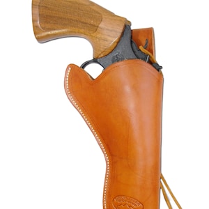 May include: A tan leather holster with a revolver. The holster is stitched with white thread and has a smooth finish. The revolver has a wooden grip and a black barrel. The holster is designed to hold the revolver securely.