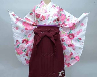 May include: A white and pink floral kimono with a maroon and white embroidered hakama. The kimono has long sleeves and a wide, flowing silhouette. The hakama is a traditional Japanese skirt-like garment worn over the kimono.