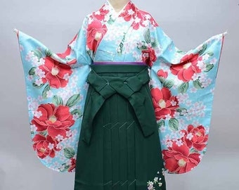 May include: A green and blue Japanese kimono with a floral pattern. The kimono has a wide, flowing sleeve and a sash tied at the waist. The sash is decorated with a small, embroidered design.