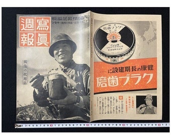 May include: A vintage magazine cover featuring a black and white photo of a soldier holding a canteen. The magazine is titled "Weekly Report" in Japanese. The cover also features an advertisement for "Club" shoe polish with the text "For a long-lasting healthy shine, Club Shoe Polish" in Japanese.