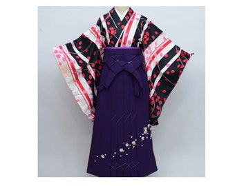 May include: A purple and black Japanese kimono with a pink and white floral pattern. The kimono has a long, flowing skirt and a wide, flowing sleeve.