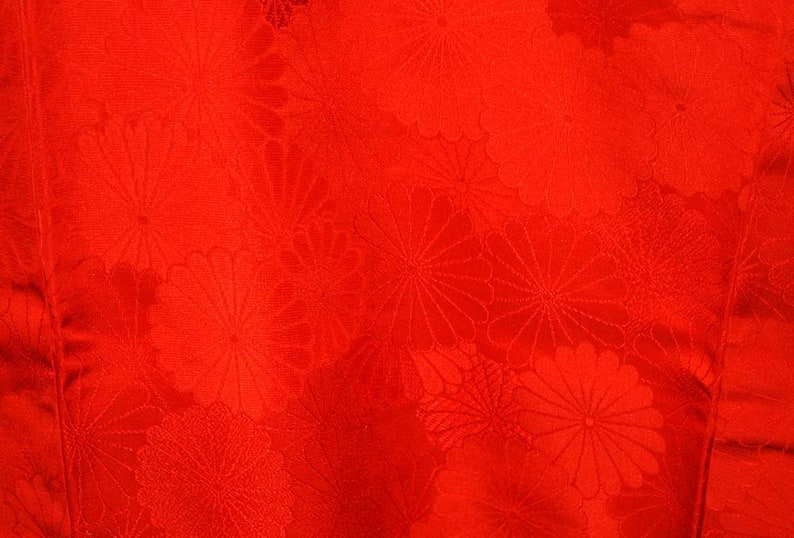 May include: Red fabric with a repeating pattern of stylised flowers.