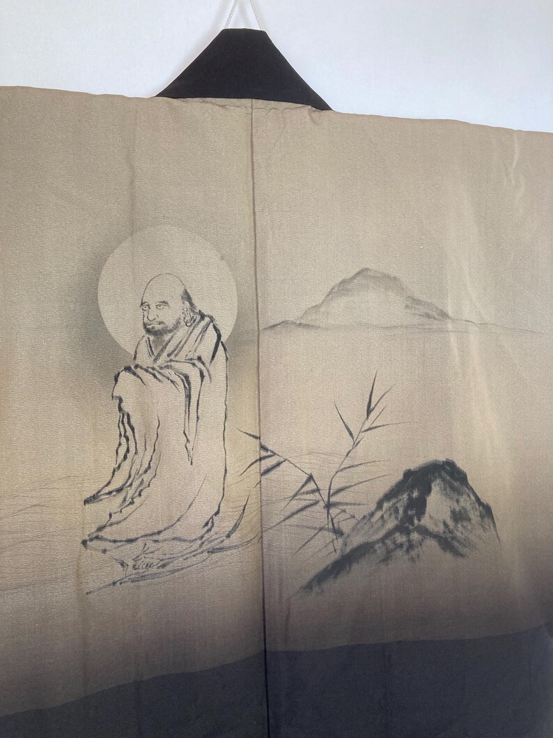 May include: A traditional Japanese kimono with a black collar and a beige background. The kimono features a hand-painted design of a man meditating in a mountain landscape with bamboo.