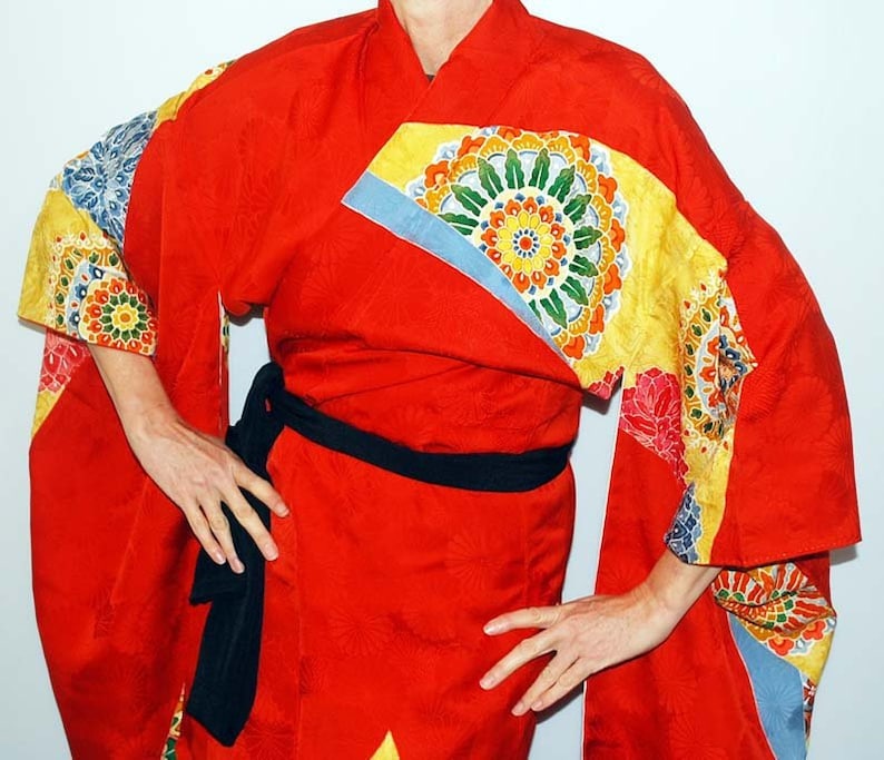 May include: A red kimono with a black sash and colourful floral patterns. The kimono has a traditional Japanese design with a wide collar and long sleeves.