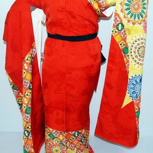 May include: A red kimono with a colourful geometric pattern. The kimono has long sleeves and a sash.