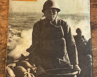 May include: Vintage Japanese magazine cover featuring a soldier in a helmet, holding a steering wheel-like object, with other soldiers in the background. The cover has Japanese text and is in sepia tones, evoking a historical feel.