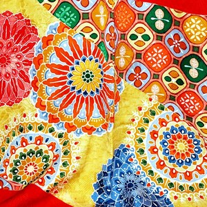 May include: A colourful fabric with a repeating pattern of flowers and geometric shapes. The fabric is yellow, red, blue, green, and white.