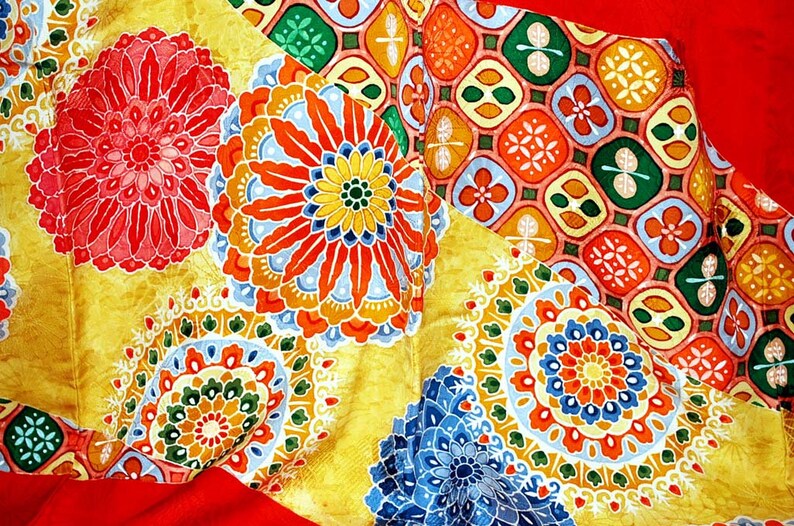 May include: A colourful fabric with a repeating pattern of flowers and geometric shapes. The fabric is yellow, red, blue, green, and white.