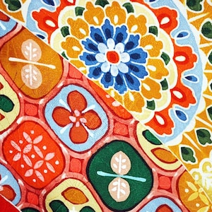 May include: A colourful fabric with a repeating pattern of geometric shapes and flowers. The fabric is a mix of red, orange, yellow, green, blue and white.